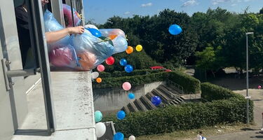 Bunte Luftballons fliegen aus dem Fenster
