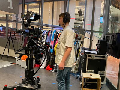 Ein Schüler steht ausgerüstet mit Headset hinter der Kamera