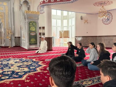 Mehrere Schüler sitzen zusammen auf dem Boden in der Moschee