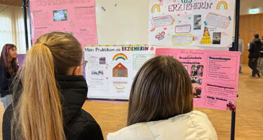 Zwei Schülerinnen begutachten eine Plakatwand