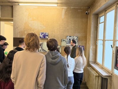 Schüler stehen in einem Raum bestückt mit Bildern und Infotafeln