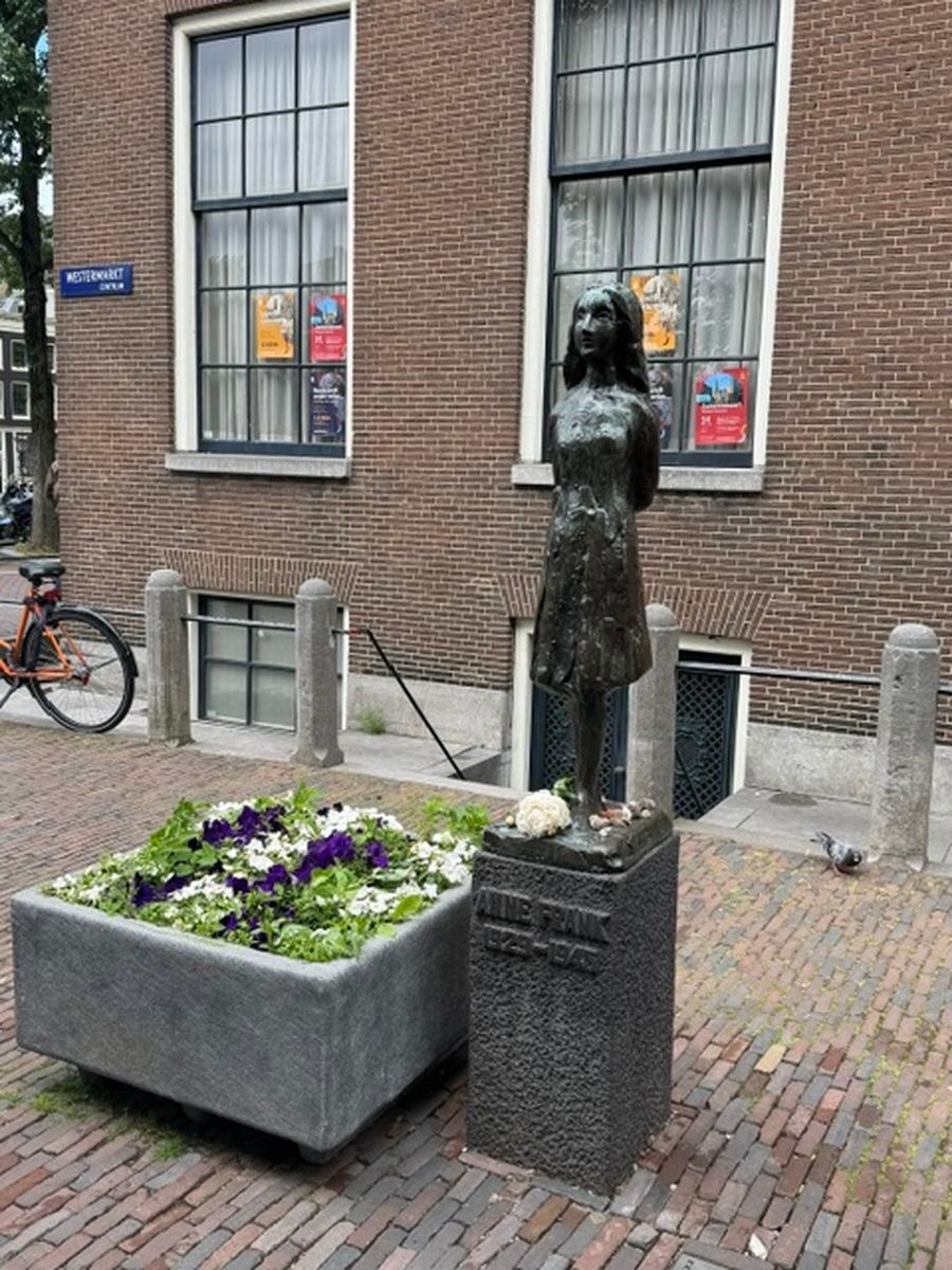 Anne Frank Statue neben Blumen