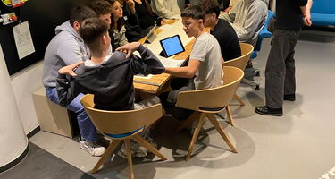 Die Schüler sitzen versammelt an einem Tisch im Studio