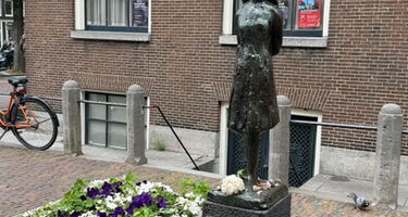 Anne Frank Statue neben Blumen