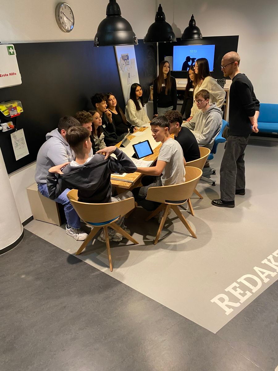 Die Schüler sitzen versammelt an einem Tisch im Studio