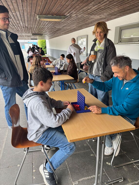 Erwachsene und Schüler spielen Vier gewinnt