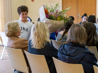 Ein Schüler überreicht einen bunten Blumenstrauß